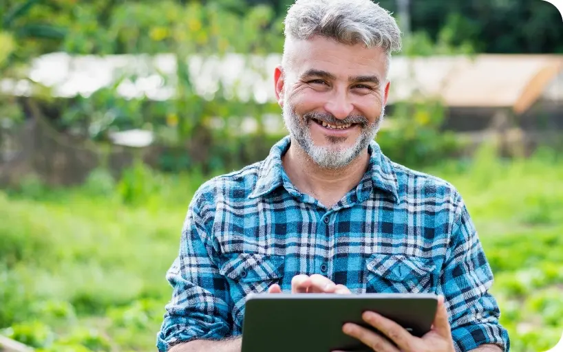 Homem sorrindo no campo segurando tablet